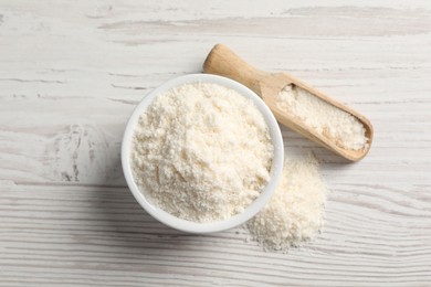 Photo of Fresh coconut flour in bowl and scoop on white wooden table, top view