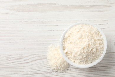 Photo of Fresh coconut flour in bowl on white wooden table, top view. Space for text