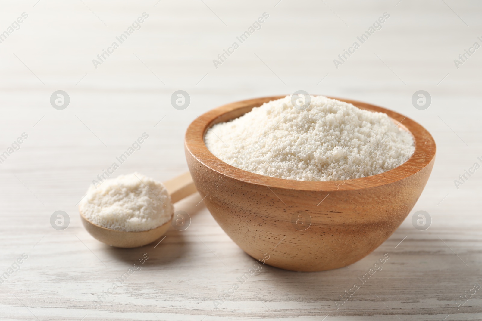 Photo of Fresh coconut flour in bowl and spoon on white wooden table