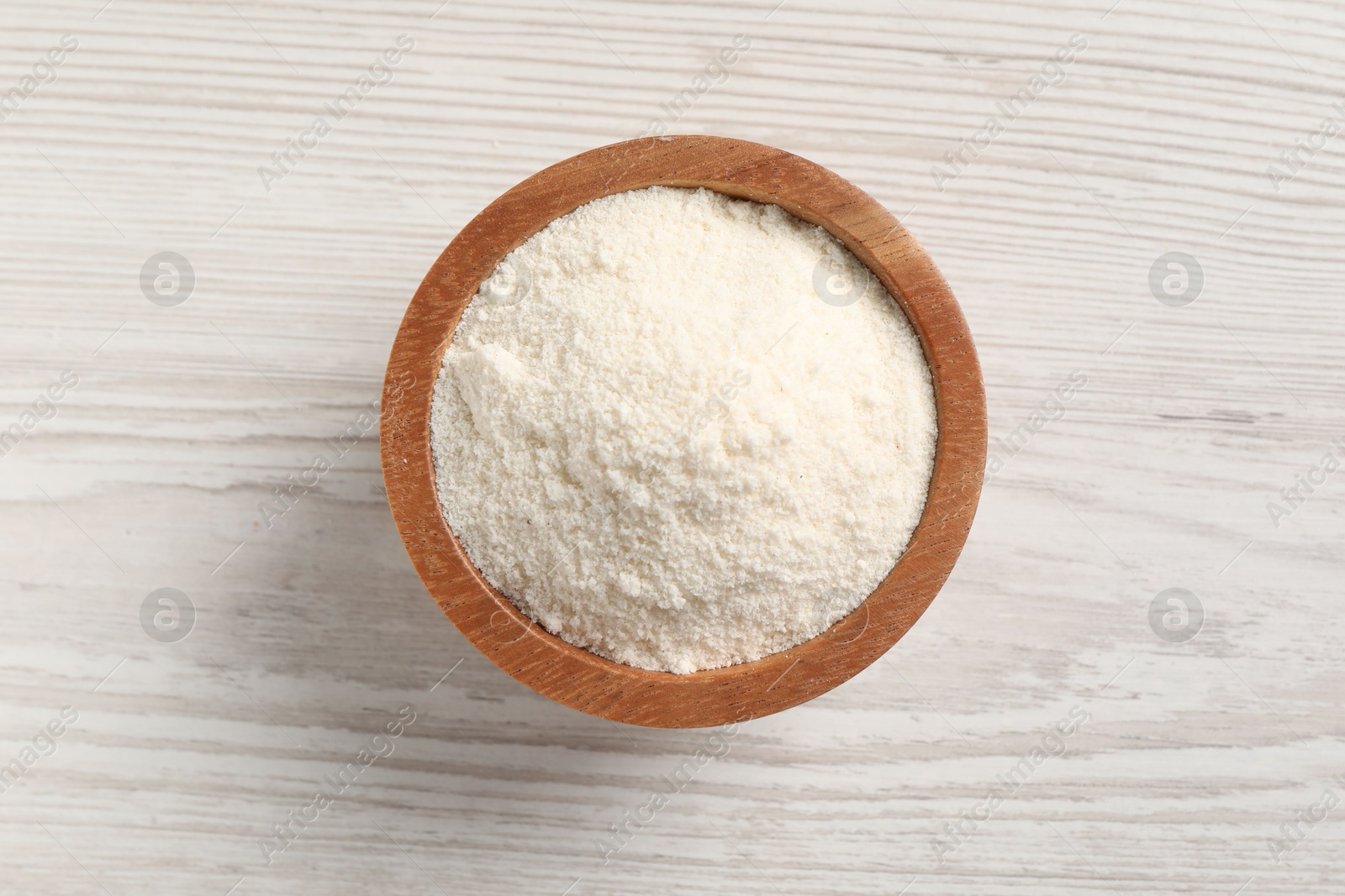 Photo of Fresh coconut flour in bowl on white wooden table, top view