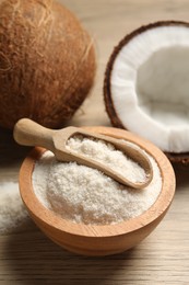 Photo of Fresh coconut flour in bowl, scoop and nut on wooden table