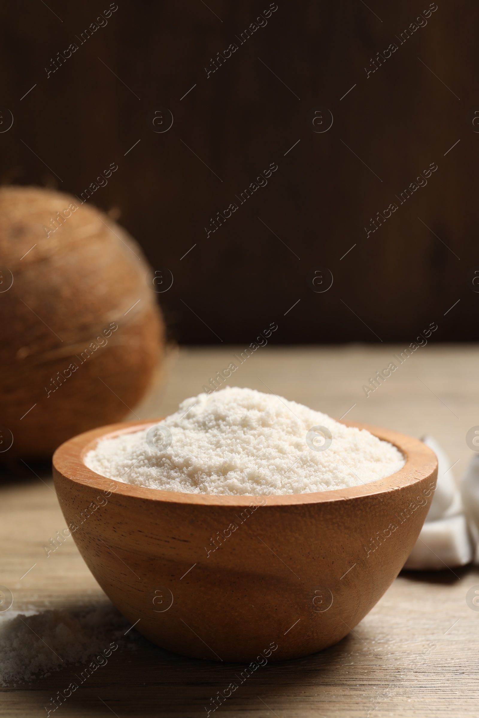 Photo of Fresh coconut flour in bowl and nut on wooden table