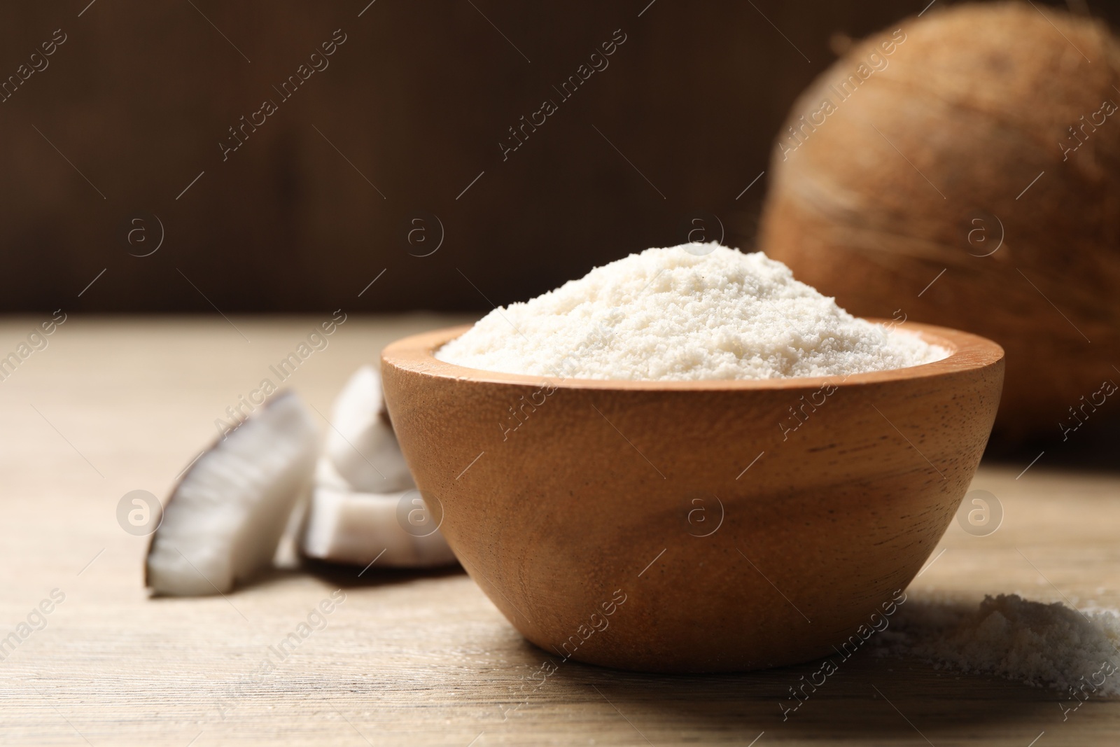 Photo of Fresh coconut flour in bowl and nut on wooden table