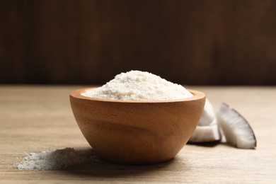 Photo of Fresh coconut flour in bowl and nut on wooden table