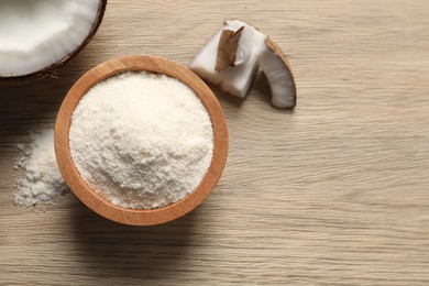 Photo of Fresh coconut flour in bowl and nut on wooden table, top view. Space for text