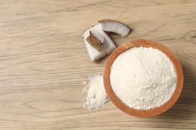 Photo of Fresh coconut flour in bowl and nut on wooden table, top view. Space for text