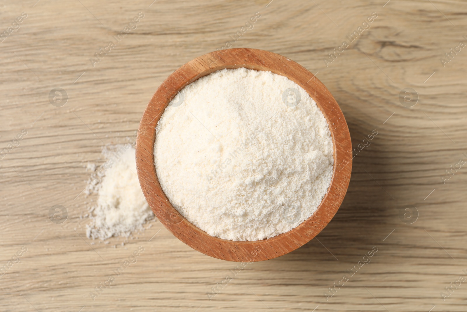 Photo of Fresh coconut flour in bowl on wooden table, top view