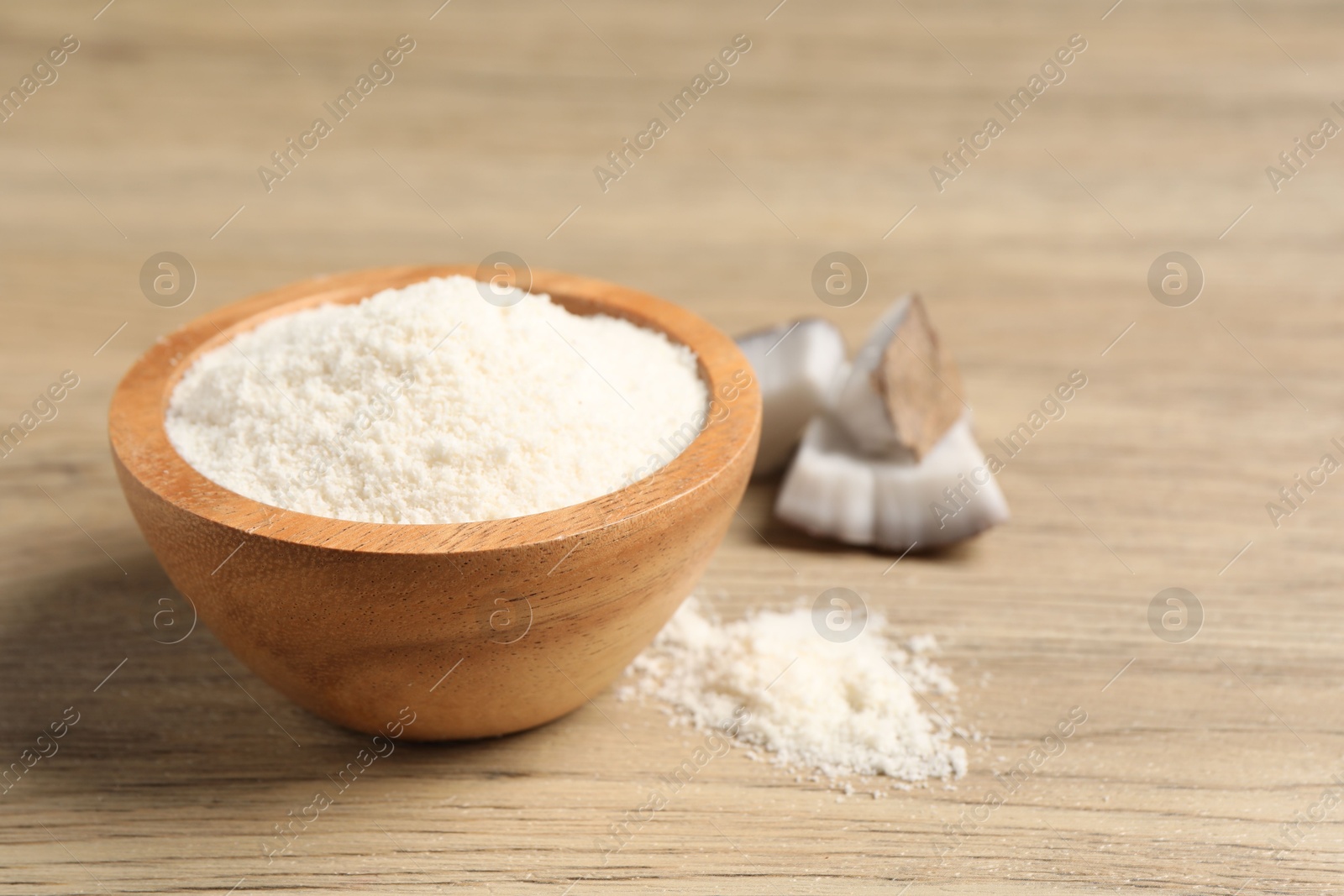 Photo of Fresh coconut flour in bowl and nut on wooden table