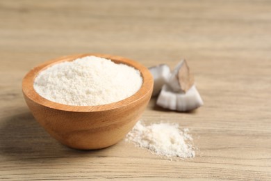 Photo of Fresh coconut flour in bowl and nut on wooden table