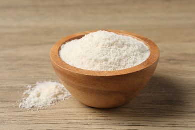 Photo of Fresh coconut flour in bowl on wooden table, closeup