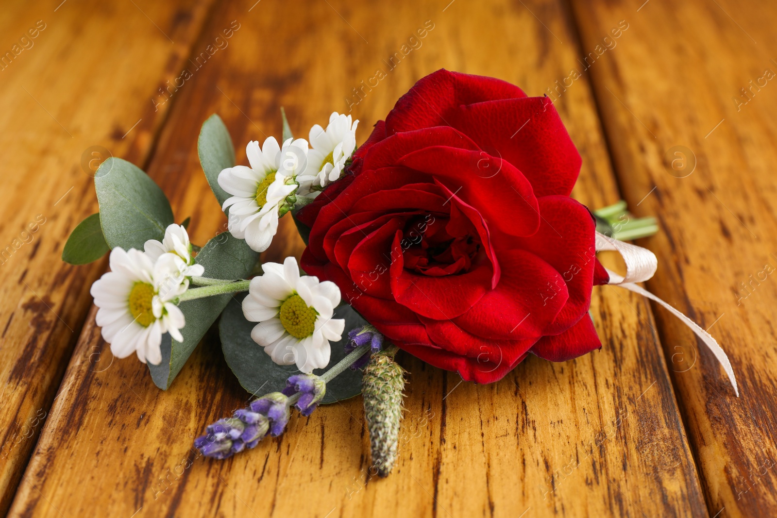 Photo of Small stylish boutonniere on wooden table, closeup