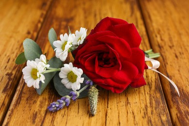 Photo of Small stylish boutonniere on wooden table, closeup