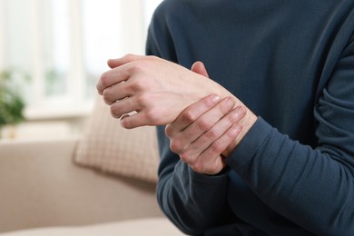 Photo of Man suffering from pain in hand indoors, closeup