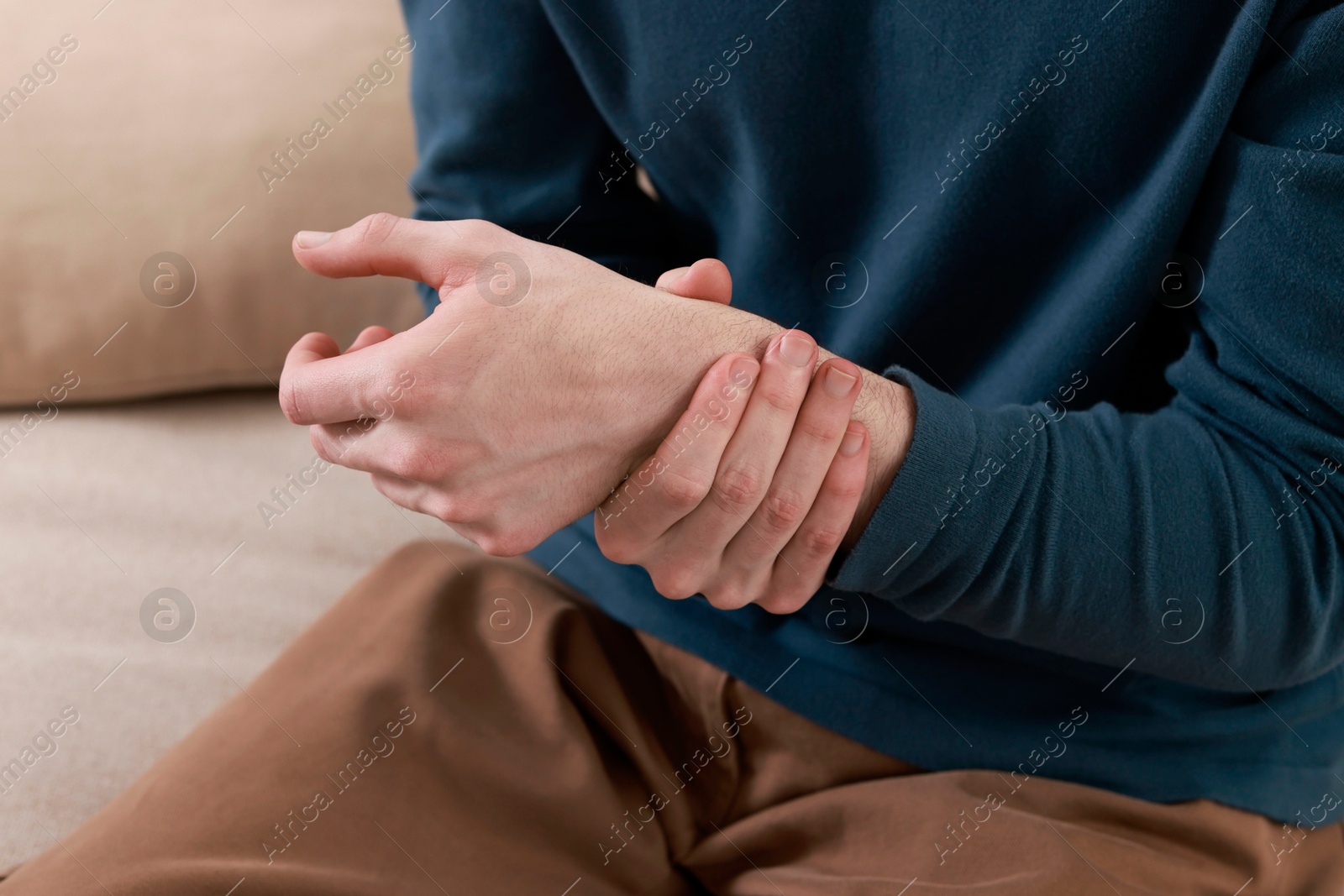 Photo of Man suffering from pain in hand indoors, closeup