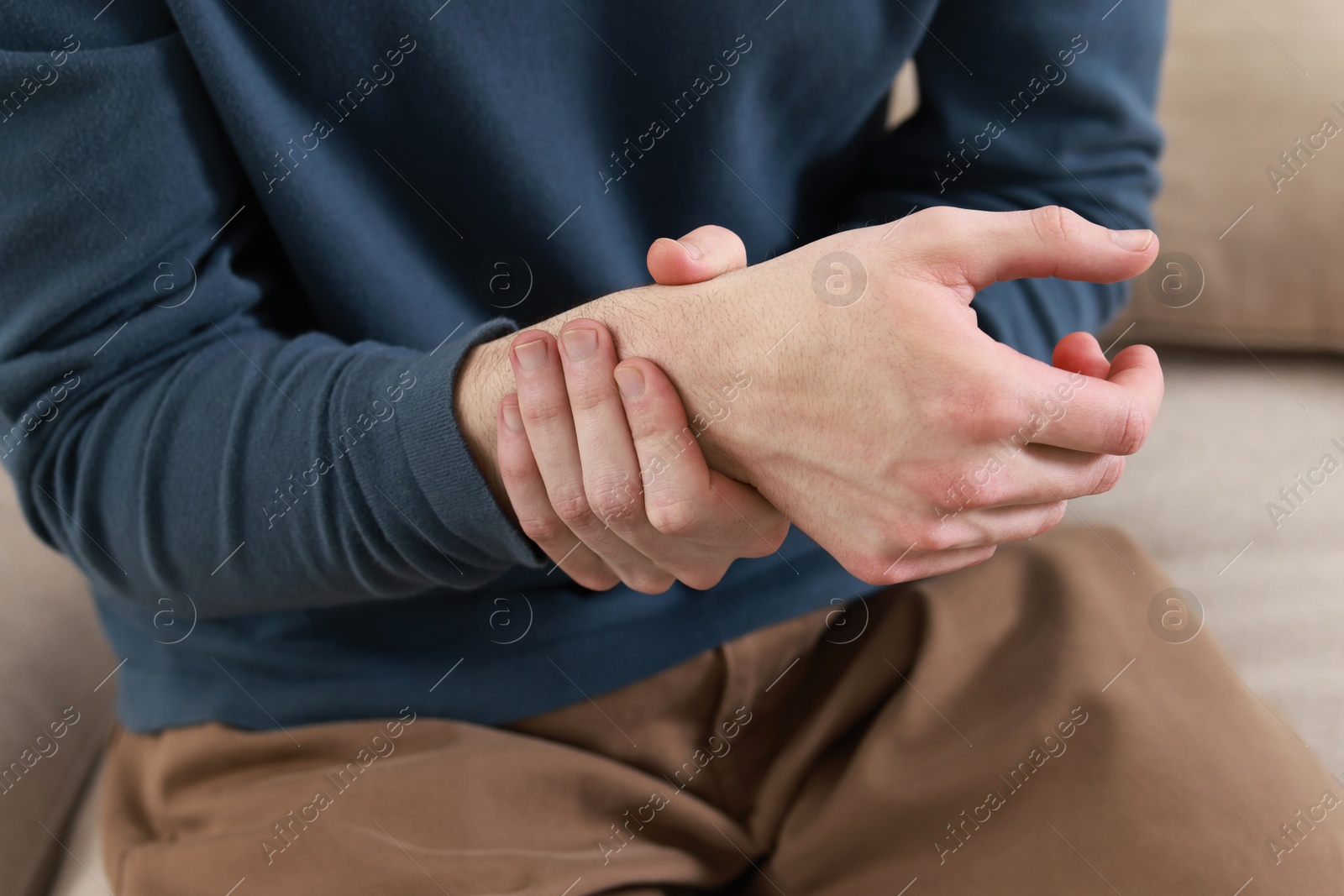 Photo of Man suffering from pain in hand indoors, closeup