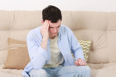 Man suffering from headache on sofa at home