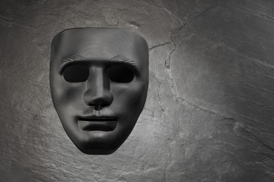 Photo of Plastic face mask on black slate surface, top view and space for text. Theatrical performance