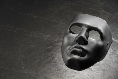 Plastic face mask on black slate surface, space for text. Theatrical performance