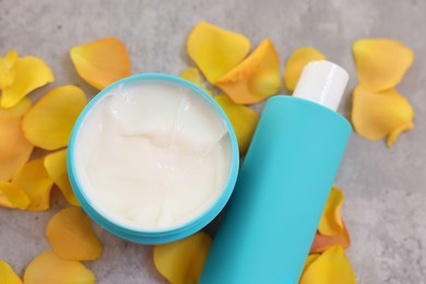 Photo of Cosmetic products and yellow petals on gray table, above view