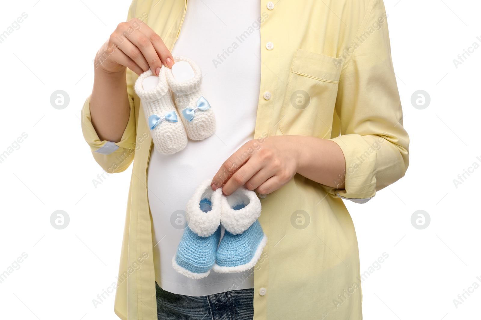 Photo of Expecting twins. Pregnant woman holding two pairs of baby shoes on white background, closeup