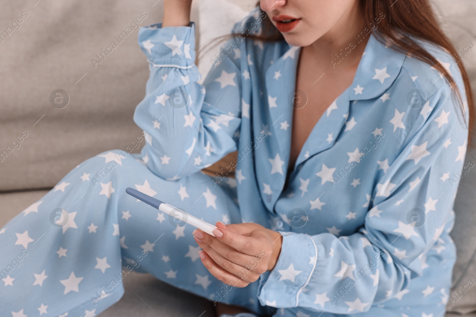 Photo of Young woman with pregnancy test on sofa at home, closeup