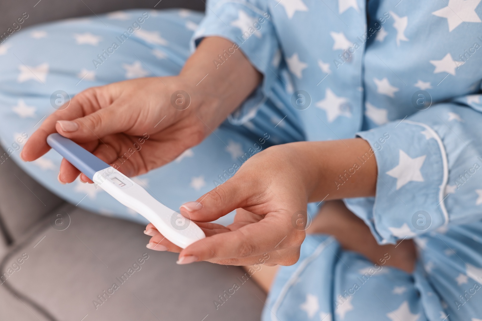 Photo of Young woman with pregnancy test on sofa at home, closeup