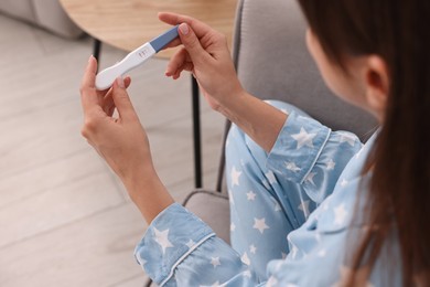 Photo of Young woman with pregnancy test on sofa at home, closeup