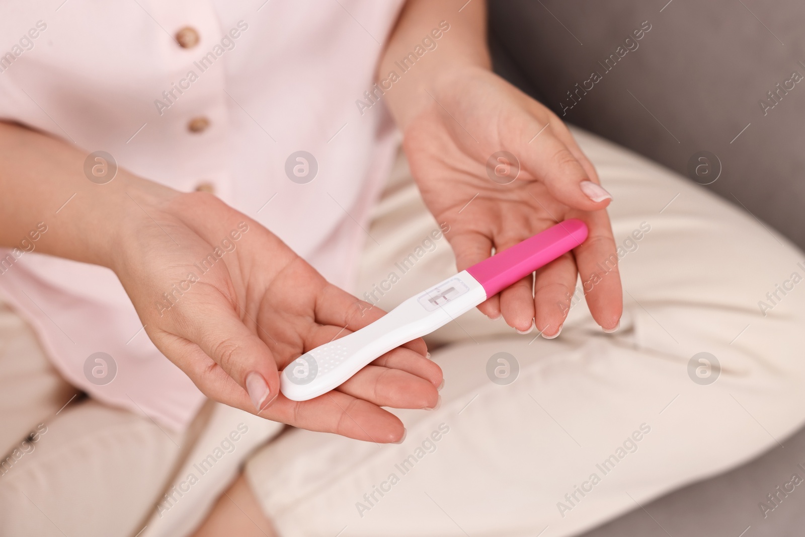 Photo of Young woman with pregnancy test on sofa at home, closeup