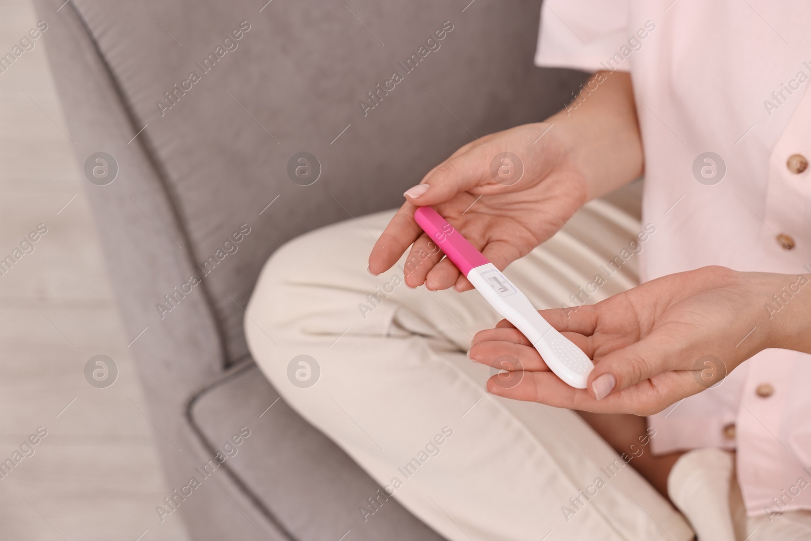 Photo of Young woman with pregnancy test on sofa at home, closeup