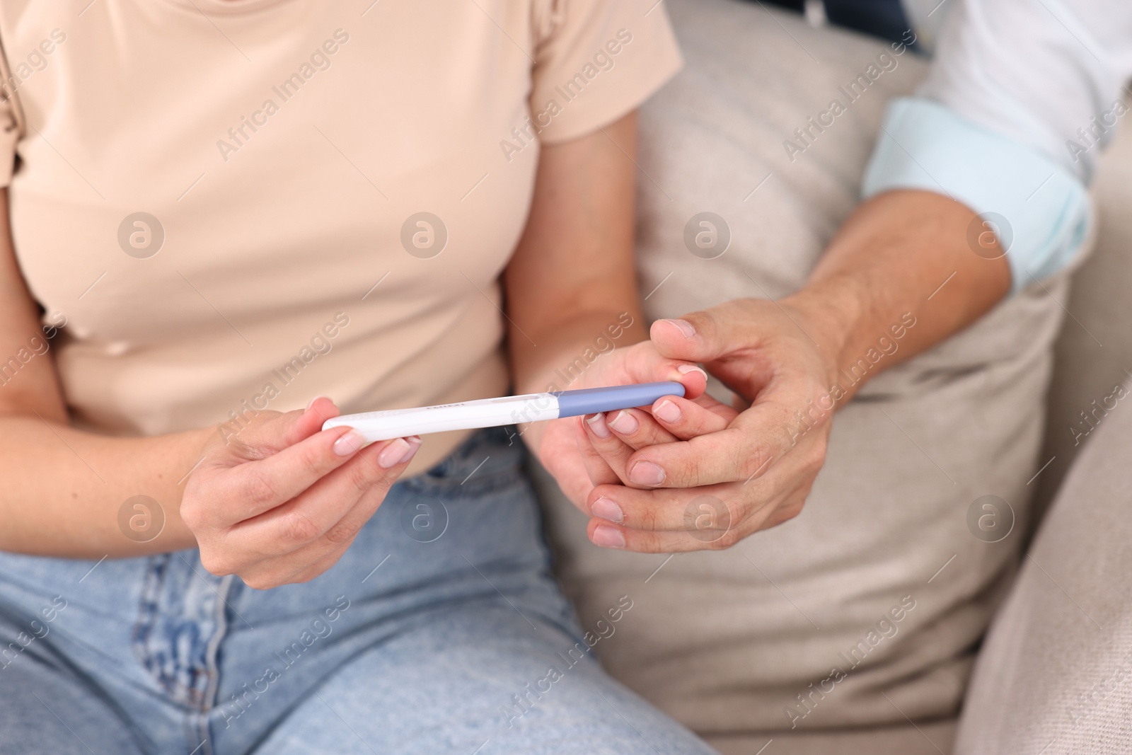 Photo of Young couple with pregnancy test on sofa, closeup