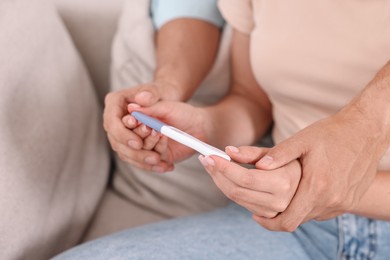 Photo of Young couple with pregnancy test on sofa, closeup