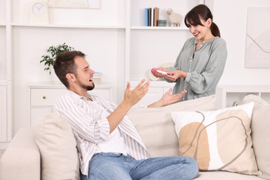 Photo of Happy young couple with pregnancy test on sofa at home