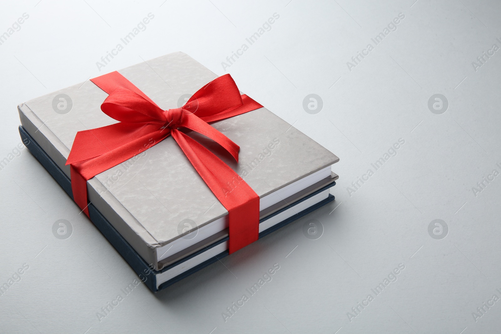 Photo of Books tied with red ribbon on grey background, closeup. Perfect gift