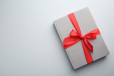 Photo of Book tied with red ribbon on grey background, top view with space for text. Perfect gift