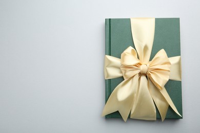 Photo of Book tied with golden ribbon on grey background, top view with space for text. Perfect gift