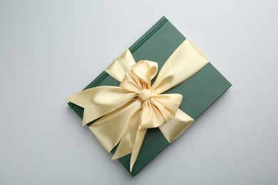 Photo of Book tied with golden ribbon on grey background, top view. Perfect gift