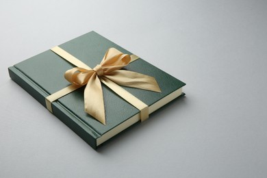 Book tied with golden ribbon on grey background. Perfect gift