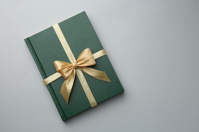 Photo of Book tied with golden ribbon on grey background, top view with space for text. Perfect gift