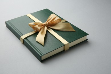 Photo of Book tied with golden ribbon on grey background. Perfect gift