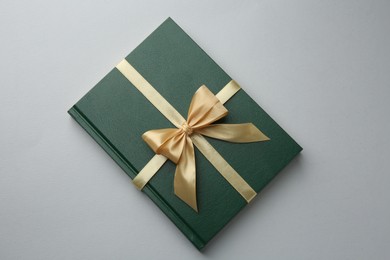 Photo of Book tied with golden ribbon on grey background, top view. Perfect gift