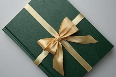 Photo of Book tied with golden ribbon on grey background, top view. Perfect gift