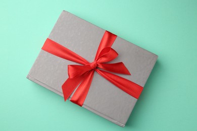 Book tied with red ribbon on green background, top view. Perfect gift