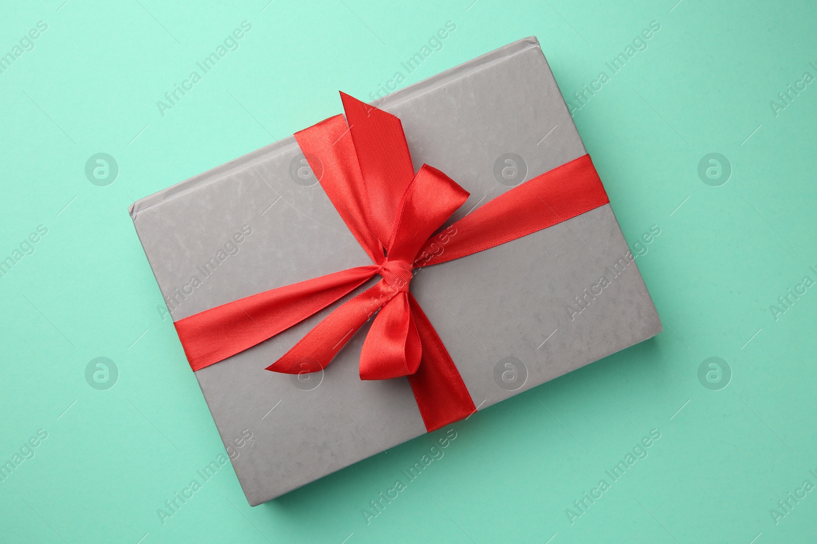 Photo of Book tied with red ribbon on green background, top view. Perfect gift