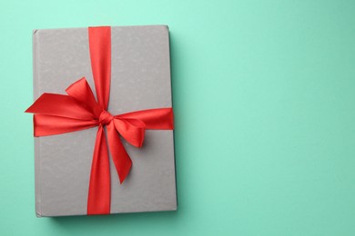 Book tied with red ribbon on green background, top view with space for text. Perfect gift