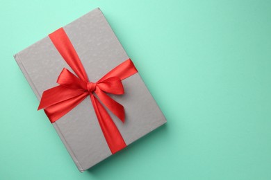 Photo of Book tied with red ribbon on green background, top view with space for text. Perfect gift