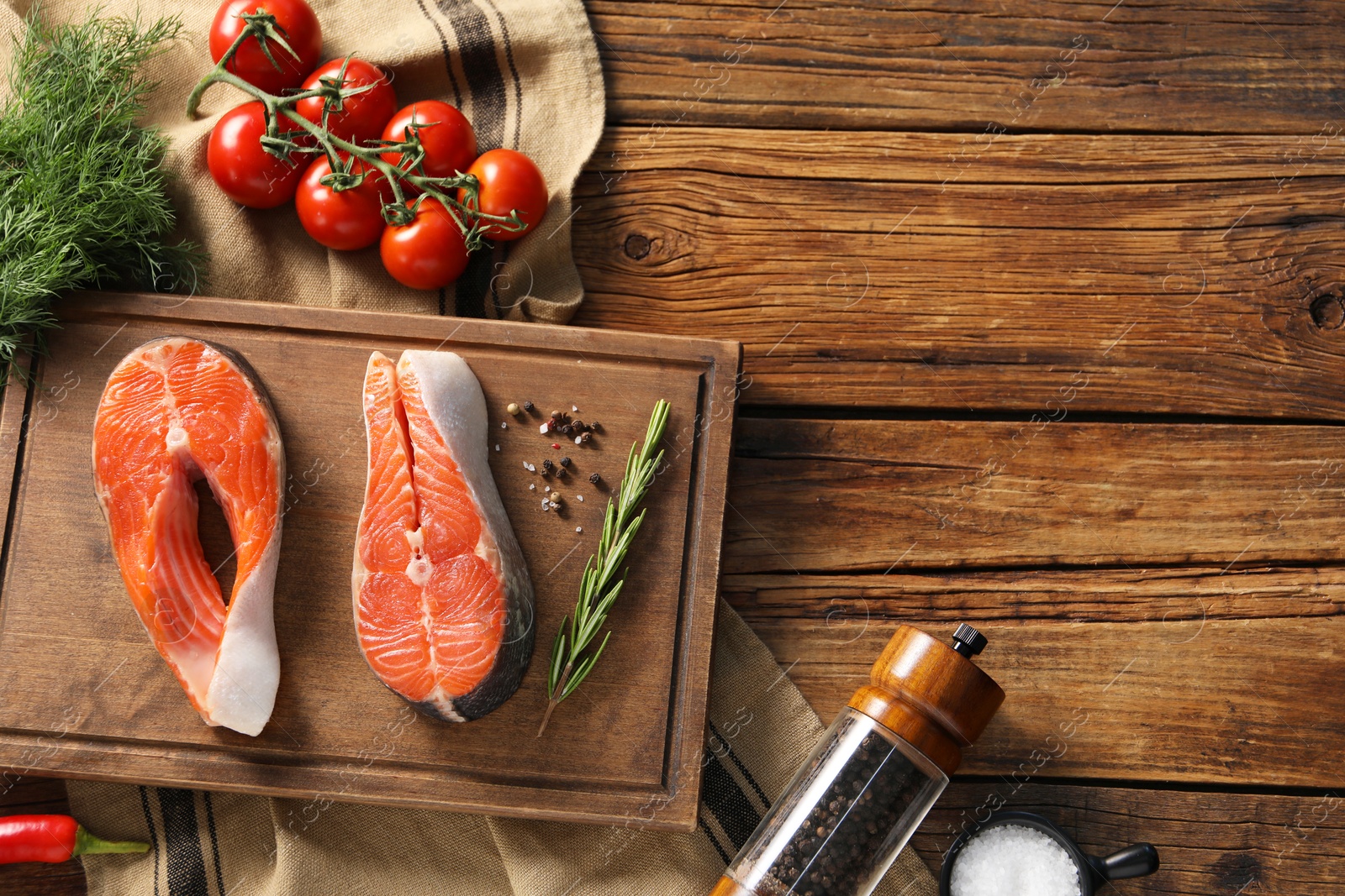 Photo of Fresh salmon steaks, spices and products on wooden table, flat lay. Space for text