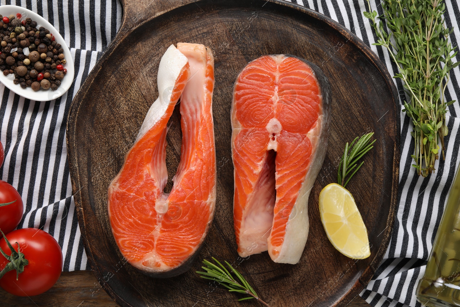 Photo of Fresh salmon steaks, peppercorns and products on wooden table, top view