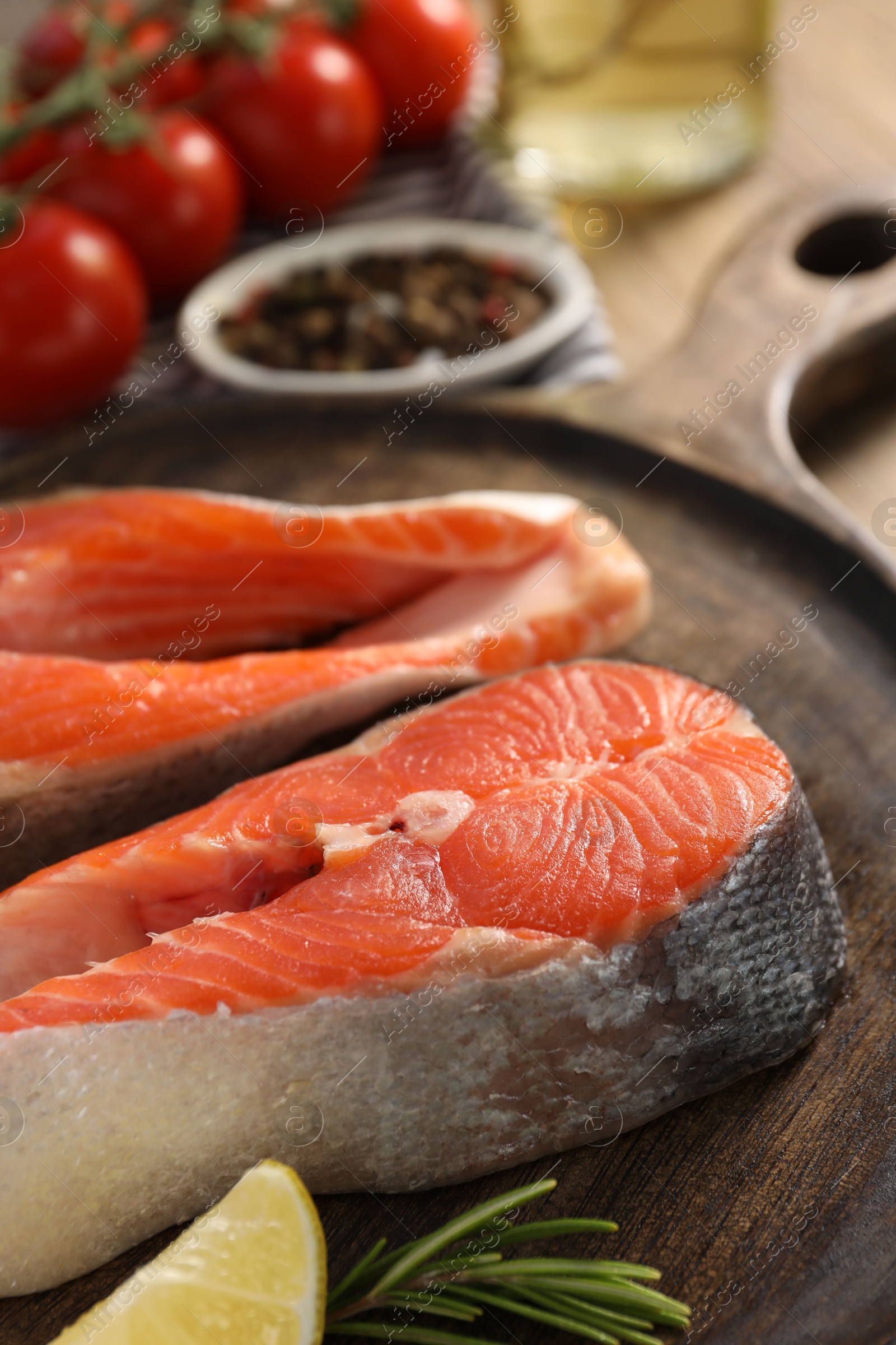 Photo of Board with fresh salmon steaks, lemon and rosemary on table, closeup