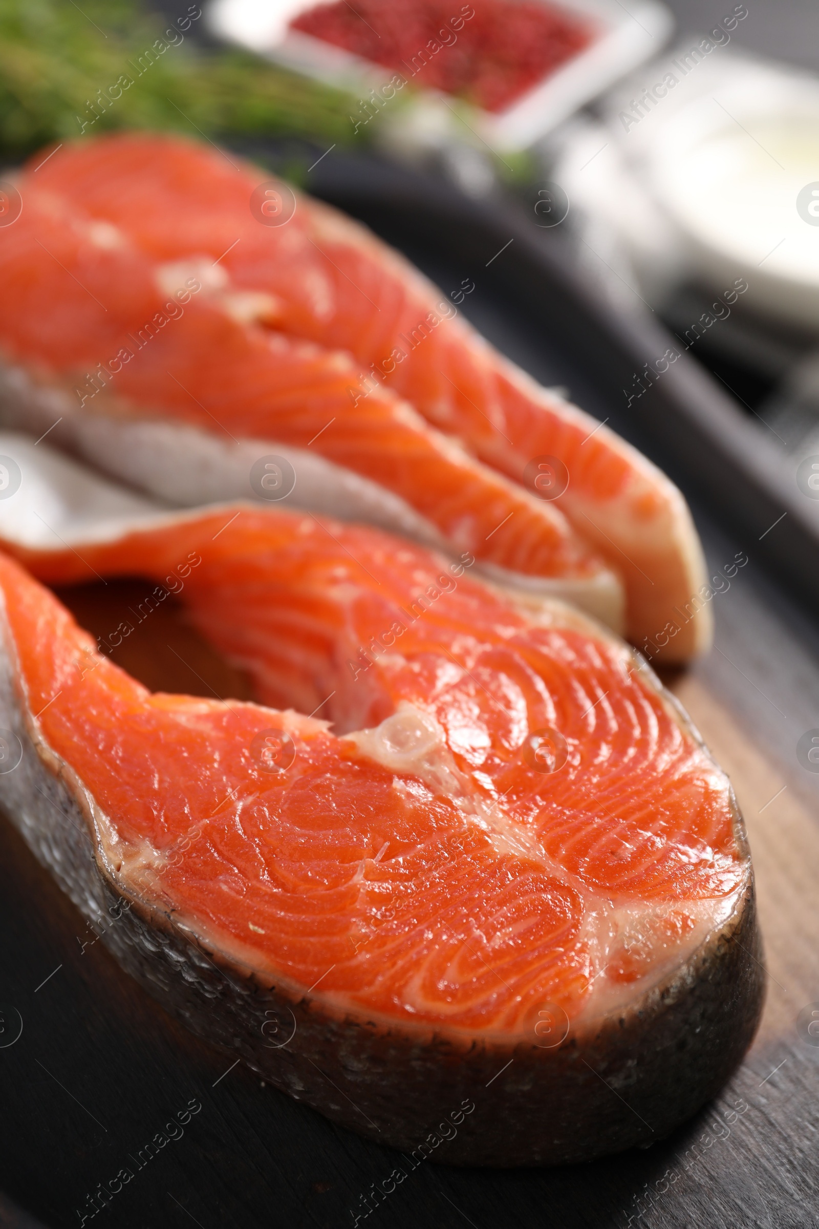 Photo of Board with fresh salmon steaks on table, closeup