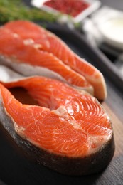 Photo of Board with fresh salmon steaks on table, closeup